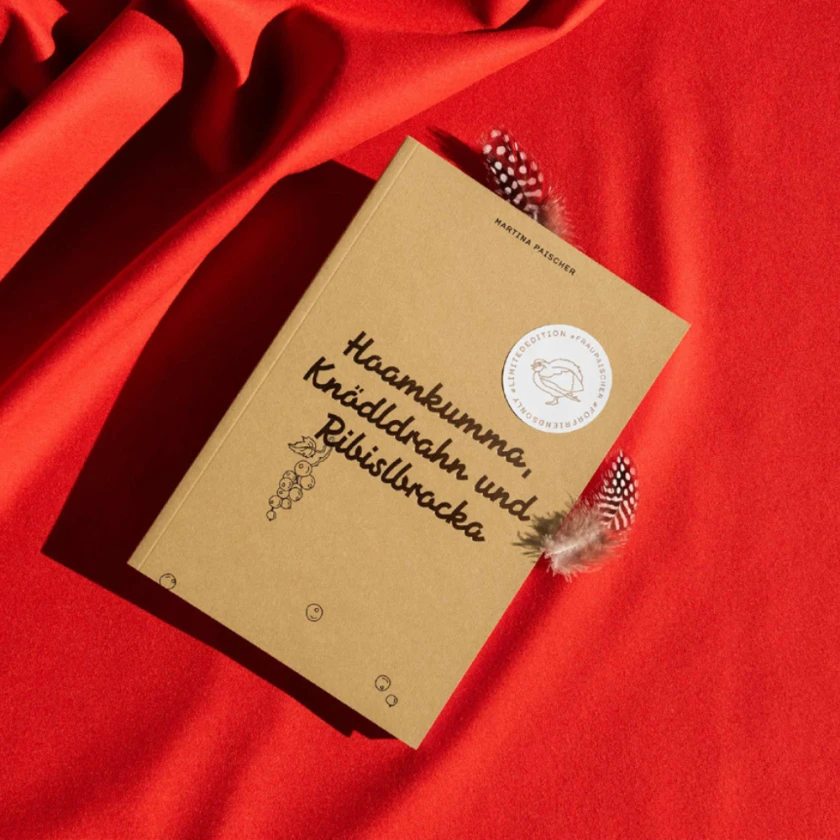 Das Buch Hoamkumma auf einem roten Hintergrund.