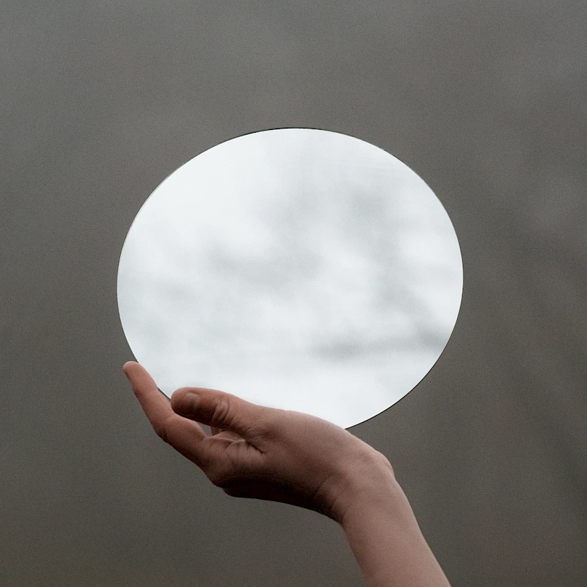 Eine Hand, die einen Spiegel balanciert aus der Referenz Level von PASSING.BIRD.