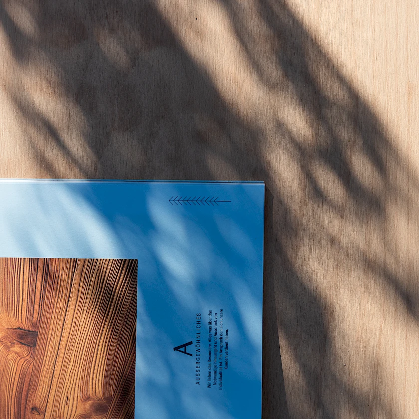 Eine Detailaufnahme einer Broschüre von Admonter auf einer Holzplatte.